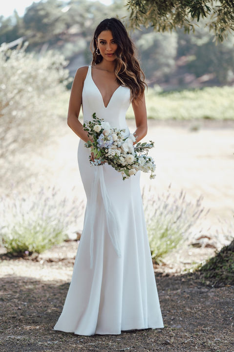outdoor photo of woman wearing white allure romance designer wedding dress
